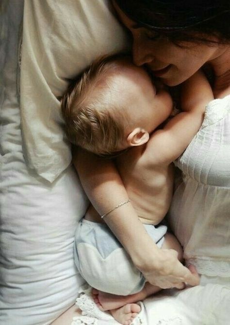 Una madre abraza a su bebé mientras descansan juntos en la cama